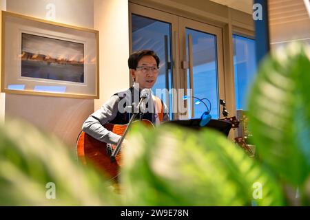 (231227) -- CHANGCHUN, 27. Dezember 2023 (Xinhua) -- Woo Kyong-Jei, ein südkoreanischer Barista, spielt Gitarre in einem Café in Changchun, nordöstlicher Provinz Jilin, 27. Dezember 2023. In den letzten Jahren hat der Nordosten die innovationsorientierte Entwicklungsstrategie aktiv umgesetzt. Viele ausländische Freunde haben Chancen erkannt und beschlossen, sich hier niederzulassen, um ihren Träumen nachzugehen. Sie leben in der Region, haben die rasche wirtschaftliche und soziale Entwicklung erlebt und haben inzwischen ihre eigenen Anstrengungen zur vollständigen Wiederbelebung des Nordostchinesischen beigetragen. (Xinhua/Yan Linyun) Stockfoto