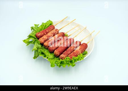 Die köstlichen Bratwürste gemischt mit Mehl und Gewürzen und Salat auf Gericht mit weißem Hintergrund. Frittierte Fleischbällchen aus Fleisch. Asiatische Straße F Stockfoto