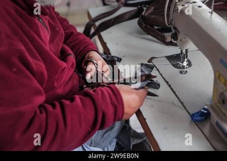 Ein palästinensischer Schneider namens Abu Adam Dolah verwendet eine Nähmaschine mit Pedalbedienung, die er aufgrund von Stromknappheit entwickelt Hat Ein palästinensischer Schneider namens Abu Adam Dolah verwendet eine Nähmaschine mit Pedalbedienung, die er aufgrund von Stromknappheit entwickelt hat, da Israel am 27. Dezember 2023 in Rafah, Gaza, die Macht blockiert. Gashda befestigte Fahrradpedale an seiner Nähmaschine so, dass er die Maschine ohne Strom benutzen konnte. Foto: Bashar Taleb apaimages Rafah Gazastreifen palästinensisches Gebiet 271223 Rafah BT 0017 Copyright: XapaimagesxBasharxTalebxapaimagesx Stockfoto