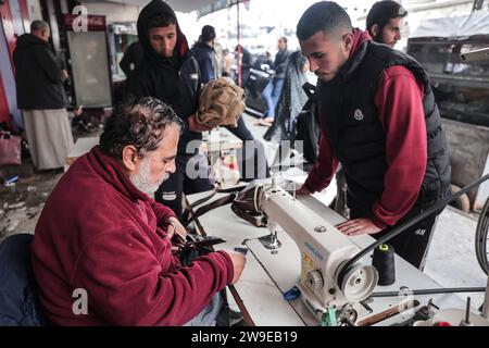 Ein palästinensischer Schneider namens Abu Adam Dolah verwendet eine Nähmaschine mit Pedalbedienung, die er aufgrund von Stromknappheit entwickelt Hat Ein palästinensischer Schneider namens Abu Adam Dolah verwendet eine Nähmaschine mit Pedalbedienung, die er aufgrund von Stromknappheit entwickelt hat, da Israel am 27. Dezember 2023 in Rafah, Gaza, die Macht blockiert. Gashda befestigte Fahrradpedale an seiner Nähmaschine so, dass er die Maschine ohne Strom benutzen konnte. Foto: Bashar Taleb apaimages Rafah Gazastreifen palästinensisches Gebiet 271223 Rafah BT 0016 Copyright: XapaimagesxBasharxTalebxapaimagesx Stockfoto