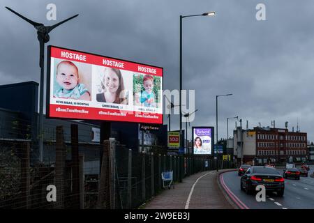 Propeller Park, 400 North Circular Road, 27. Dezember 2023. Eine rotierende digitale Plakatkampagne des "Geiseln- und Vermisstenfamilien Forum UK", in der Fotos von einigen der entführten israelischen Zivilisten gezeigt werden, die am 7. Oktober 2023 von der Hamas aufgenommen wurden. Die Kampagne zielt darauf ab, die Not der Männer, Frauen und Kinder, die noch immer als Geiseln im Gazastreifen gehalten werden, in die Öffentlichkeit zu rücken. Foto: Amanda Rose/Alamy Live News Stockfoto