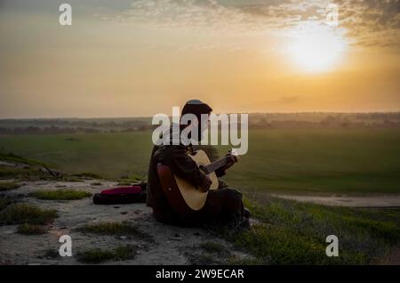 Israel. Dezember 2023. Der israelische Soldat spielt mit seiner Gitarre während des Sonnenuntergangs entlang der südlichen Grenze zwischen Israel und Gaza. Quelle: Ilia Yefimovich/dpa/Alamy Live News Stockfoto