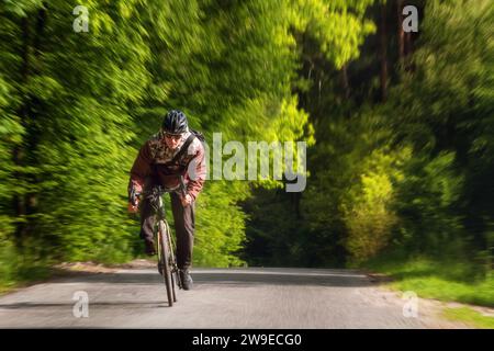 Radfahrer radeln aktiv auf der Straße im Wald. Bewegungsunschärfeeffekt. Sport. Aktivitäten im Freien. Stockfoto