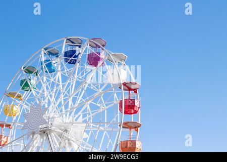 Riesenrad mit mehrfarbigen Fahrerhäusern auf blauem Himmel Stockfoto