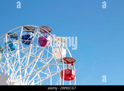 Riesenrad mit mehrfarbigen Fahrerhäusern auf blauem Himmel Stockfoto