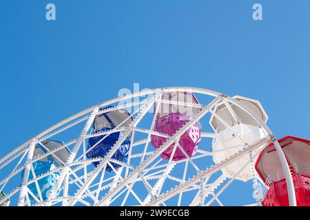 Riesenrad mit mehrfarbigen Fahrerhäusern auf blauem Himmel Stockfoto