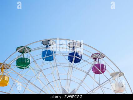 Riesenrad mit mehrfarbigen Fahrerhäusern auf blauem Himmel Stockfoto