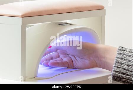 Frauenhand in UV-Lampe. Verfahren zur Trocknung der gelpolierung. Maniküre im Schönheitssalon. Stockfoto