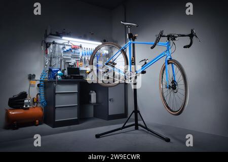 Fahrradwerkstatt zur Reparatur von Fahrrädern. Fahrrad hängt an einem Reparaturständer im Hintergrund einer Werkbank mit professionellen Werkzeugen. Fahrradservice. Stockfoto