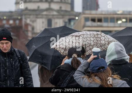 Menschen trotzen dem Wetter, wenn sie die Millennium Bridge in London überqueren. Sturm Gerrit wird am Mittwoch starke Winde und starke Regenfälle in viele Teile Großbritanniens bringen, wobei auch winterliche Gefahren wahrscheinlich sind, warnten die Wettervorhersagen. Bilddatum: Mittwoch, 27. Dezember 2023. Stockfoto