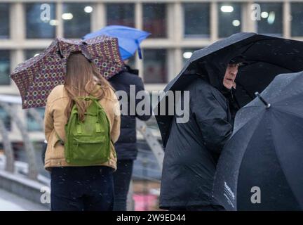 Menschen trotzen dem Wetter, wenn sie die Millennium Bridge in London überqueren. Sturm Gerrit wird am Mittwoch starke Winde und starke Regenfälle in viele Teile Großbritanniens bringen, wobei auch winterliche Gefahren wahrscheinlich sind, warnten die Wettervorhersagen. Bilddatum: Mittwoch, 27. Dezember 2023. Stockfoto