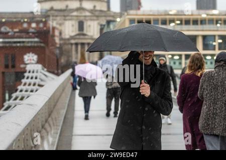 Menschen trotzen dem Wetter, wenn sie die Millennium Bridge in London überqueren. Sturm Gerrit wird am Mittwoch starke Winde und starke Regenfälle in viele Teile Großbritanniens bringen, wobei auch winterliche Gefahren wahrscheinlich sind, warnten die Wettervorhersagen. Bilddatum: Mittwoch, 27. Dezember 2023. Stockfoto