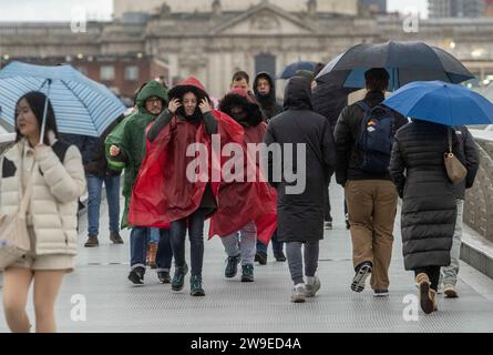 Menschen trotzen dem Wetter, wenn sie die Millennium Bridge in London überqueren. Sturm Gerrit wird am Mittwoch starke Winde und starke Regenfälle in viele Teile Großbritanniens bringen, wobei auch winterliche Gefahren wahrscheinlich sind, warnten die Wettervorhersagen. Bilddatum: Mittwoch, 27. Dezember 2023. Stockfoto