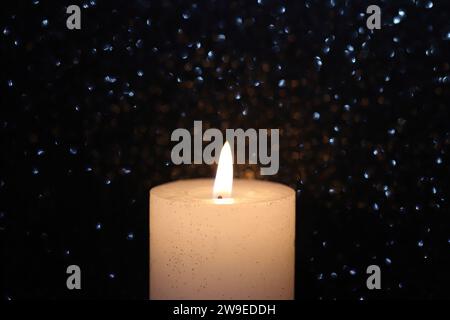 Nahaufnahme einer weißen Kerze vor einem schwarz schimmernden Hintergrund, Seitenansicht, Kopierraum Stockfoto
