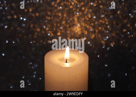 Nahaufnahme einer brennenden Kerze vor dunklem Hintergrund, Blick von oben, Kopierraum Stockfoto