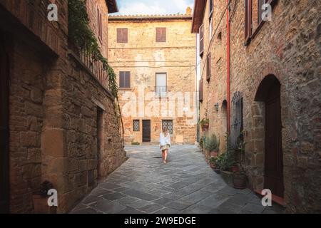 Eine junge blonde Touristenin erkundet die Hintergassen des malerischen und charmanten toskanischen Dorfes Monticchiello in der Toskana, Italien. Stockfoto