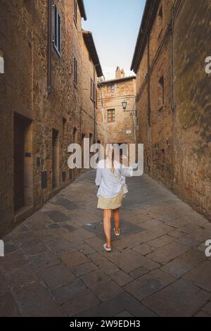 Eine junge blonde Touristenin erkundet die Hintergassen des malerischen und charmanten toskanischen Dorfes Monticchiello in der Toskana, Italien. Stockfoto