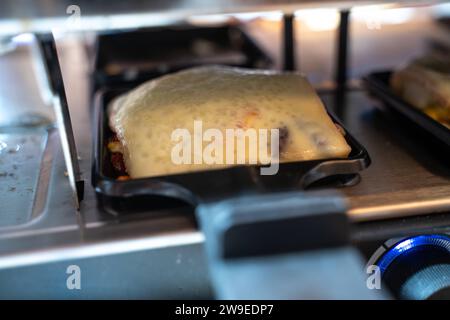 Bayern, Deutschland - 24. Dezember 2023: Raclettekäse schmelzen auf einem elektrischen Raclettekäse am schmelzen in einem elektrischen Raclettgrill Stockfoto