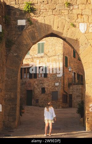 Eine junge blonde Touristenin erkundet die Hintergassen des malerischen und charmanten toskanischen Dorfes Monticchiello in der Toskana, Italien. Stockfoto