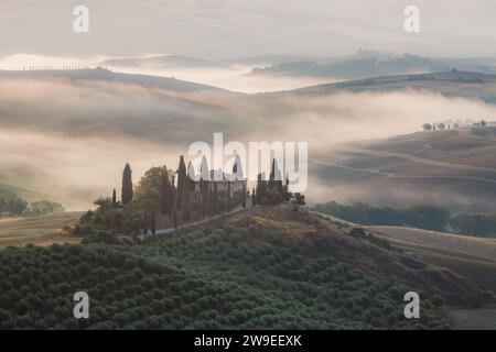 Stimmungsvoller Sonnenaufgang Nebel durch das Tal von Val d'Orcia und ein rustikales Bauernhaus in der malerischen Landschaft und sanften Hügeln der ländlichen Toskana Stockfoto