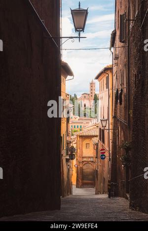 Blick auf die Basilika Santa Maria dei Servi durch eine malerische und enge Seitenstraße in der historischen toskanischen Altstadt von Siena, Toskana, Italien. Stockfoto