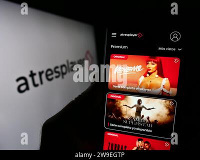 Person, die ein Mobiltelefon hält und die Webseite des spanischen Video-Streaming-Unternehmens Atresplayer vor dem Geschäftslogo zeigt. Konzentrieren Sie sich auf die Mitte des Telefondisplays. Stockfoto