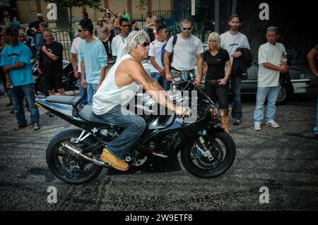 Ein Mann fährt ein leistungsstarkes Motorrad ohne Helm, während eine Menschenmenge auf einem Fahrradtreffen in London, Großbritannien, zusieht Stockfoto