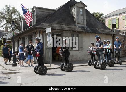 Touristen, die Segway's durch das French Quarter von New Orleans fahren, mit Lafittes an der Ecke Bourbon und St. Philips im Hintergrund. Stockfoto