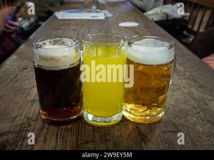 Drei Gläser verschiedener Sorten von kaltem, leckerem Bier stehen auf einem Holztisch in einem Restaurant hintereinander. Tisch für die Gesellschaft von Freunden, Platz für Text, Sele Stockfoto