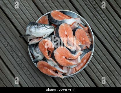 Blech aus Metall gefüllt mit großen Stücken frischen rohen atlantischen Lachs und frischem Lachskopf. Das Protein wird in Steaks geschnitten, wodurch der helle oran freigelegt wird Stockfoto