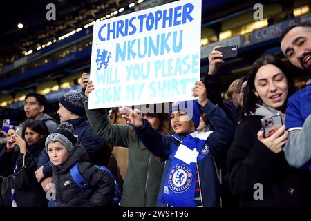 Chelsea-Fans mit einem Schild, das Christopher Nkunku bittet, ihr Trikot während des Premier League-Spiels in Stamford Bridge, London, zu unterzeichnen. Bilddatum: Mittwoch, 27. Dezember 2023. Stockfoto