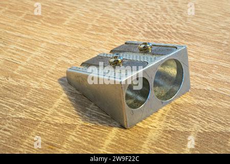 Detaillierte Aufnahme eines Bleistiftspitzers aus Metall auf einem Holztisch. Stockfoto