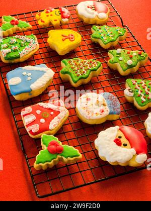 Auf einem Gittergestell vor einer orangen Arbeitsplatte wird eine bunte Präsentation mit weihnachtlichen Zuckerkeksen präsentiert Stockfoto