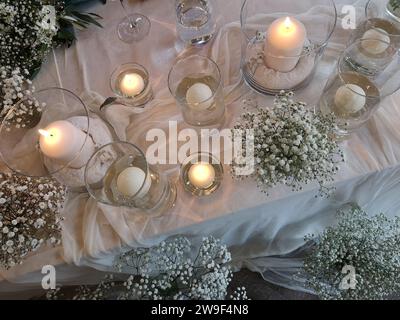 Ein kunstvoll gestalteter Stillleben-Tisch mit weißen Blumen und Kerzen Stockfoto