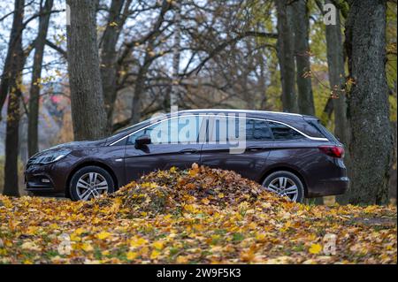 Dobele, Lettland – 3. November 2023: Opel Astra Sport Tourer auf der Straße mit Herbstlaub im Stadtpark. Herbstlandschaft Stockfoto