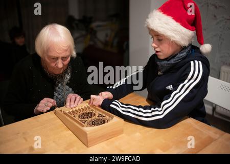 Großmutter und ihr Enkel spielen Tischplatten-Flipperspiel am Weihnachtstag in England, Großbritannien Stockfoto