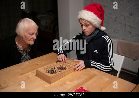 Großmutter und ihr Enkel spielen Tischplatten-Flipperspiel am Weihnachtstag in England, Großbritannien Stockfoto