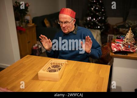 Großeltern spielen Tischplatten-Flipperspiel am Weihnachtstag, England, Großbritannien Stockfoto