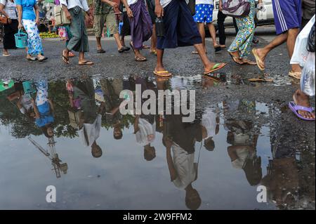 01.08.2013, Yangon, Myanmar, Asien - Menschen spiegeln sich in einer riesigen Pfütze, während sie während der Regenzeit auf einer Straße spazieren. Stockfoto