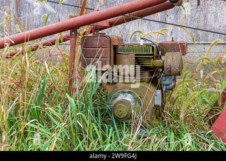 Alte, rostige Farmschnecke, die hinter der Scheune steht. Konzept für Entsorgung, Recycling, Lagerung und Schrott von Landmaschinen. Stockfoto