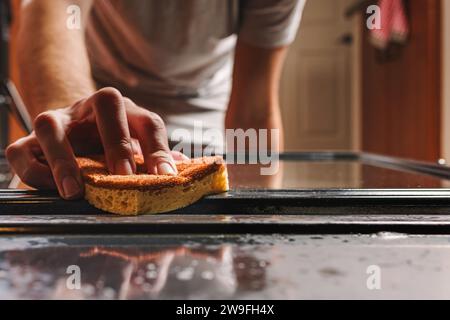 Nicht erkennbarer Mann, der den Ofen mit einem Schwamm schrubbt, Nahaufnahme, Küchenreinigung Stockfoto