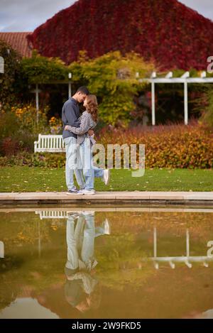 Ein junges Paar küsst und freut sich am See. Schönes junges Paar, das sich im Herbst draußen küsst. Liebevolles Paar, das in der Natur spaziert. Herbststimmung. Glücklicher Mann Stockfoto