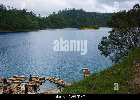 Erhöhter Horizont: Blick auf den hölzernen Pier von oben auf einen Chiapas See, azurblaues Wasser, üppige Bäume, Erdboden, entfernte Boote, Bedeckter Tag. Montebello's La Stockfoto