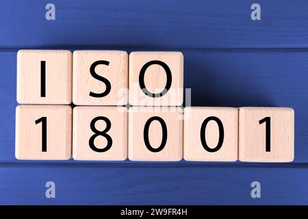 Internationale Organisation für Normung. Würfel mit Abkürzung ISO und Nummer 18001 auf blauem Holztisch, flach gelegt Stockfoto