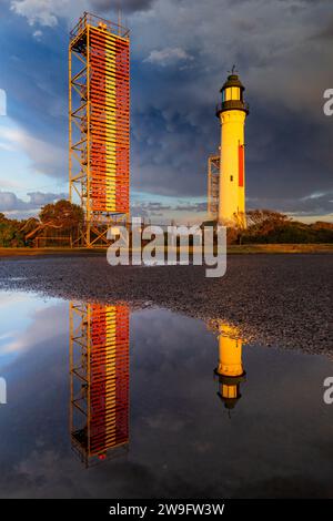 Niedriger Blick auf einen Leuchtturm und Türme, die sich in Pfützen unter einem stürmischen Himmel in Queenscliff auf der Bellarine Peninsula in Victoria, Australien, spiegeln. Stockfoto