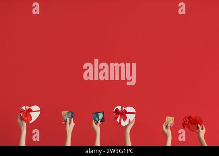 Frauen mit Geschenken und Kreditkarten auf rotem Hintergrund. Valentinstag-Feier Stockfoto