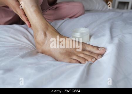 Frau, die zu Hause Vaseline auf den Füßen benutzt Stockfoto