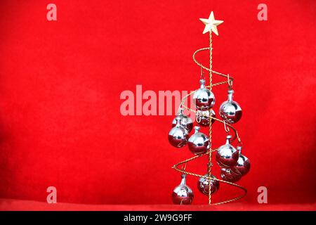 Weihnachtsbaum mit Stern und silbernen Kugeln auf rot strukturiertem Samthintergrund Stockfoto