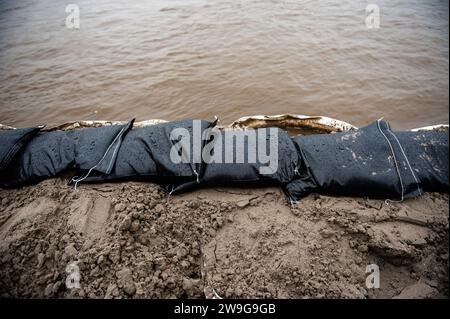 Deventer, Niederlande. Dezember 2023. Sandsäcke und Sand werden entlang des Kais platziert. Aufgrund des steigenden Wassers in der IJssel stellt die Gemeinde Deventer Sandsäcke an den Kai, um die Altstadt zu schützen. Der starke Regen, der in den letzten Monaten gefallen ist, kombiniert mit der Tatsache, dass die Alpen für diese Jahreszeit ungewöhnlich warm sind, hat die IJssel in Overijssel, Gelderland, Drenthe, Brabant und Limburg überschwemmt. Quelle: SOPA Images Limited/Alamy Live News Stockfoto
