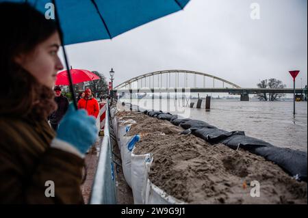 Deventer, Niederlande. Dezember 2023. Eine Frau wird gesehen, wie sie auf den Fluss blickt, der die Stadt fast überschwemmt. Aufgrund des steigenden Wassers in der IJssel stellt die Gemeinde Deventer Sandsäcke an den Kai, um die Altstadt zu schützen. Der starke Regen, der in den letzten Monaten gefallen ist, kombiniert mit der Tatsache, dass die Alpen für diese Jahreszeit ungewöhnlich warm sind, hat die IJssel in Overijssel, Gelderland, Drenthe, Brabant und Limburg überschwemmt. Quelle: SOPA Images Limited/Alamy Live News Stockfoto